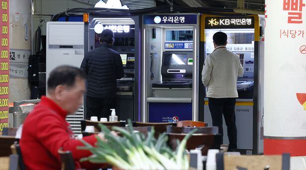 16일 시민들이 서울 시내의 한 시장 내 식당가 앞에 설치된 은행 현금인출기(ATM)를 이용하고 있다. /연합뉴스