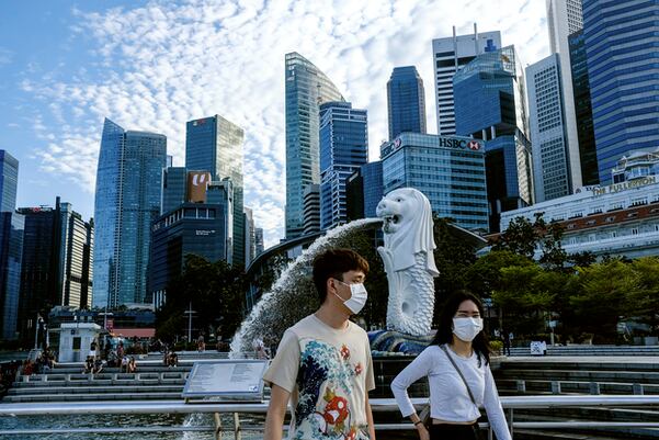 마스크를 쓴 남녀가 싱가포르의 상징인 ‘머라이언’ 분수 앞을 지나고 있다.