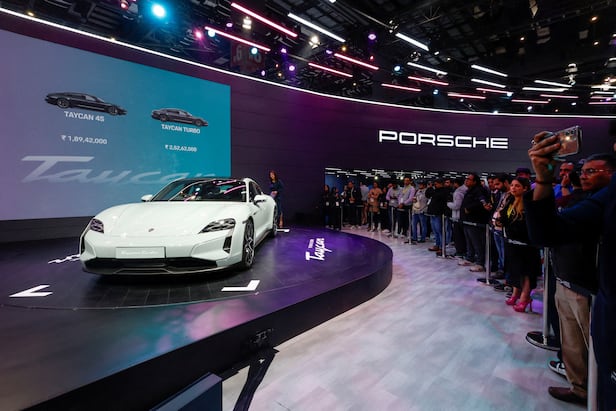 At an auto show in India, visitors and press cameramen photograph a Porsche Taycan electric vehicle (EV). /Courtesy of Yonhap News