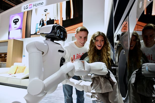 LG Electronics' home robot LG CLOi picks laundry from a basket and loads it into a washing machine at the CES 2026 exhibition hall./Courtesy of LG Electronics